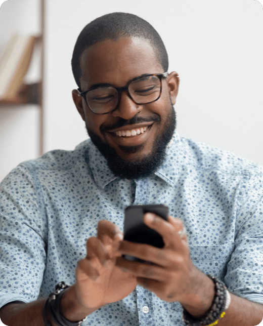 A smiling man in blue shirt looking at his phone