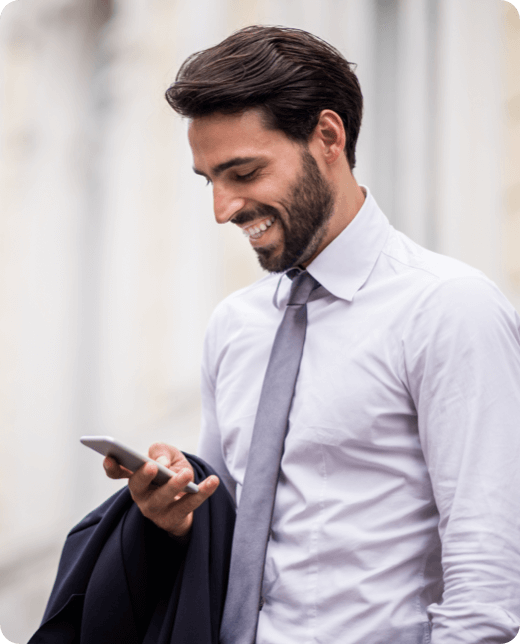 A smiling man in blue shirt looking at his phone