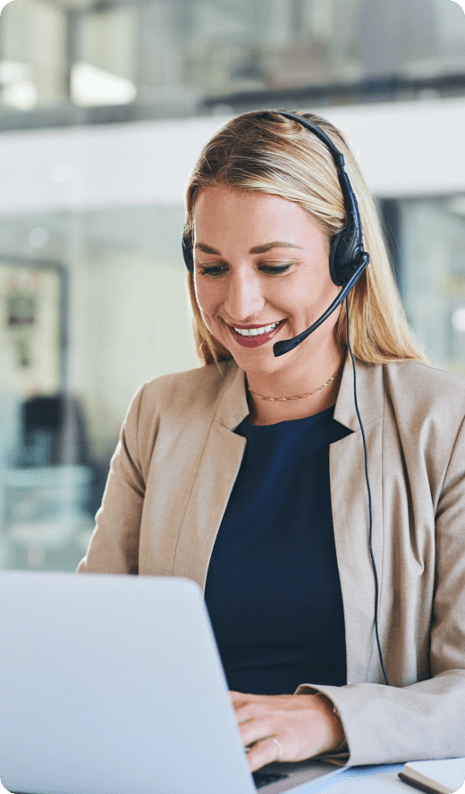 A smiling woman looking at her laptop wearing headphones