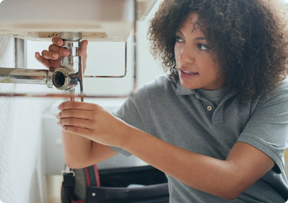 woman in curly hair fixing a plumbing issue