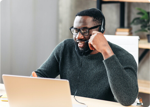 a smiling man wearing headphones and working on laptop