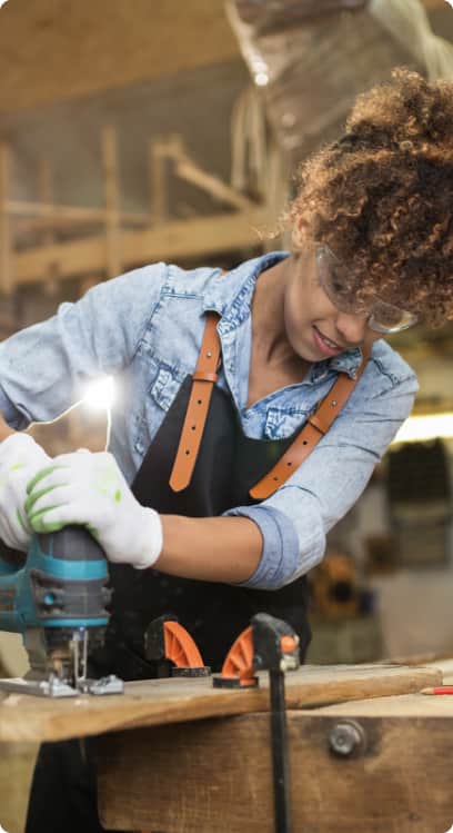 a young woman in safety gears drilling wood